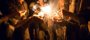 group of people in a huddle with sparklers